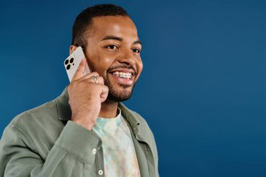 Şık bir Afrikalı Amerikalı cep telefonuyla canlı arka planda konuşuyor..