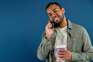 Kahve ve telefonla birden fazla iş yapan şık Afrikalı Amerikalı adam..