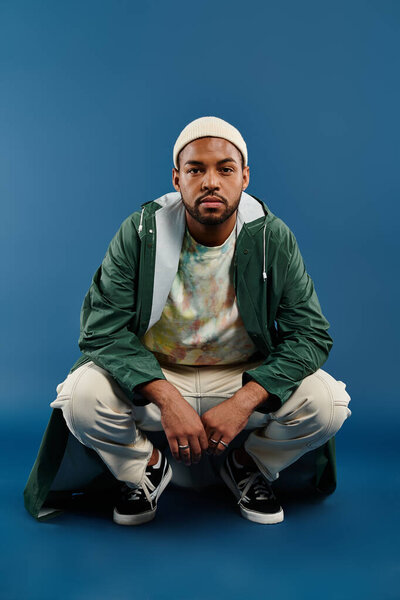 A man in a green jacket seated on the ground.