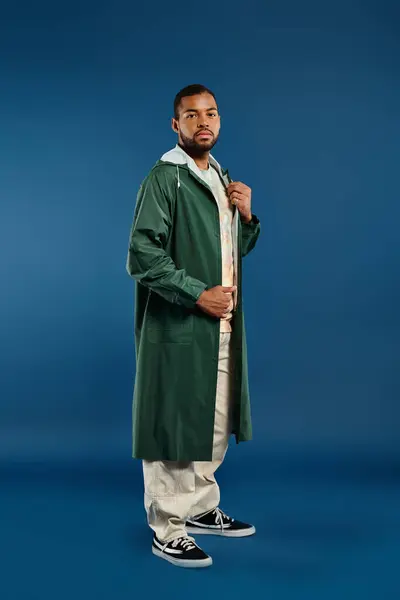 stock image African American man in green coat and white pants strikes a pose in vibrant setting.