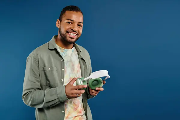 stock image Stylish man confidently holds headphones.