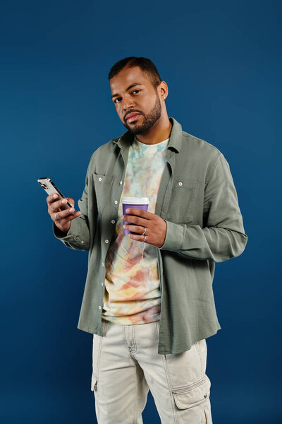 Стильный мужчина многозадачный с сотовым телефоном и кофейной чашкой.