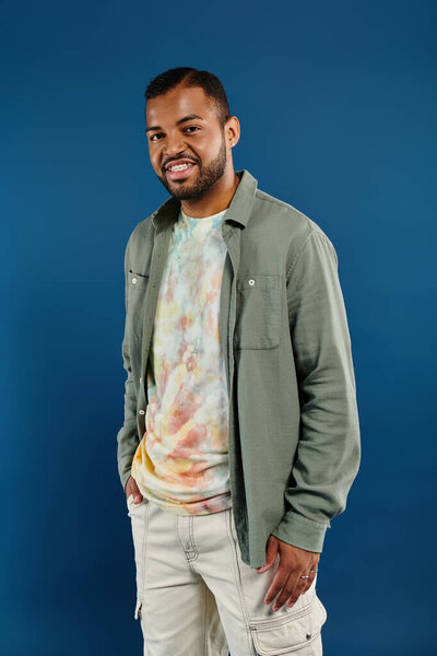 Стильный афроамериканец уверенно позирует с руками в карманах на ярком фоне.