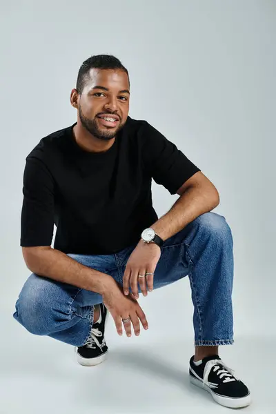 stock image African American man in black shirt and jeans striking a pose.