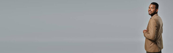 Человек торжественно стоит на светло-сером фоне.