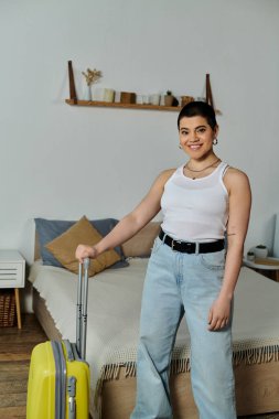 Kısa saçlı genç bir kadın sarı bir bavulun yanında duruyor, tatil ve seyahat için hazırlanıyor..
