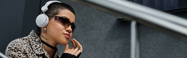 Молодая женщина в леопардовой куртке в наушниках возле современного здания.