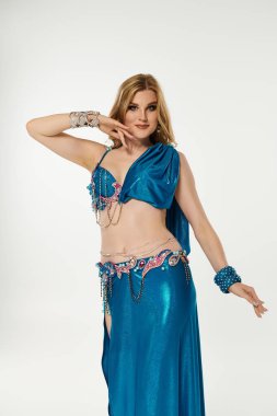 Genç bayan zarif bir şekilde canlı mavi bir kostümle göbek dansını gösteriyor..