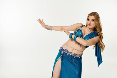 Graceful woman in blue belly dance attire sways elegantly. clipart
