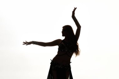 A woman in a belly dance pose with her arms raised gracefully. clipart
