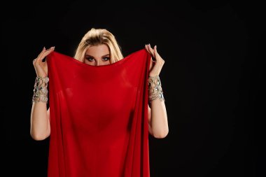 Kırmızı elbiseli büyüleyici bir kadın büyüleyici bir dans yaparken kırmızı bir bez tutuyor..