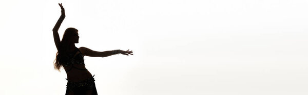 Женщина в плавном платье стоит, руки подняты в радостном танце.