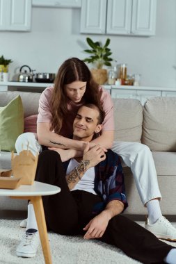 Rastgele giyinmiş bir LGBT çifti, rahat bir oturma odasında kanepede birlikte oturuyorlar..