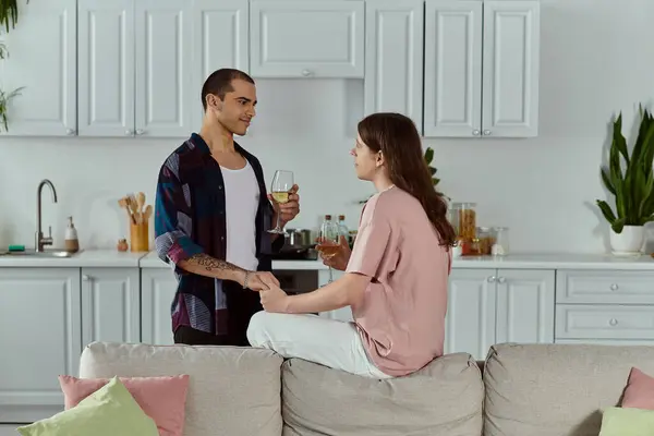 stock image A gay couple in casual clothes sit on a couch, engrossed in conversation, creating a warm and intimate atmosphere.