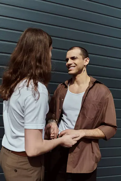 stock image A gay couple in casual clothes stand side by side, enjoying a moment together outdoors.