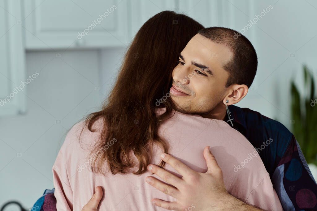 A man tenderly hugs a partner in a cozy kitchen, showing love and affection in a beautiful moment.