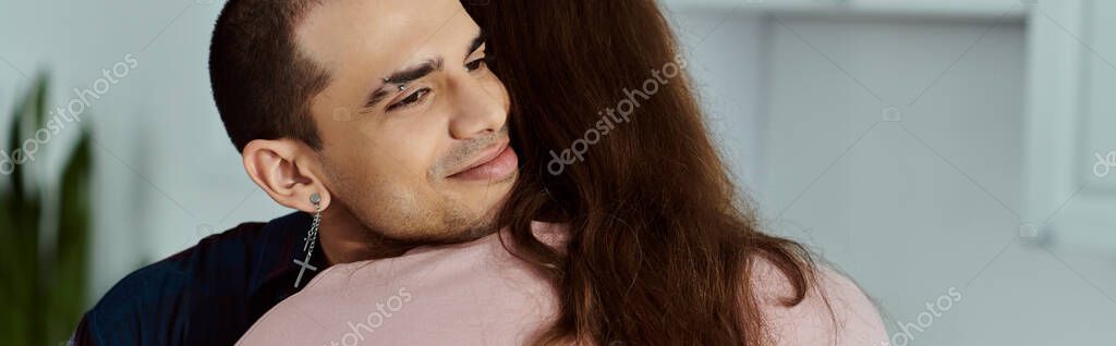 A man tenderly hugs a partner in a cozy kitchen, showing love and affection