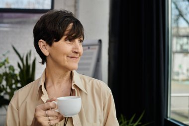 Kadın pencerede kahvenin tadını çıkarıyor..