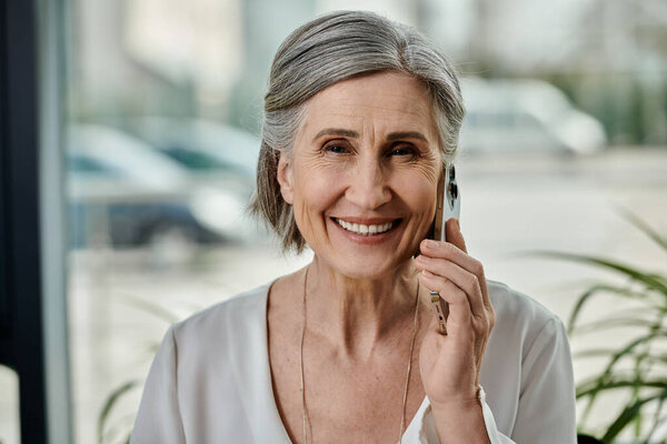 Пожилая женщина внимательно разговаривает по мобильному телефону.