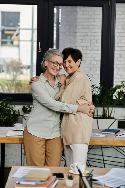 stock image Two women in office, sharing a warm hug.