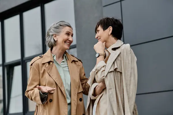 stock image Two professional women, a mature beautiful lesbian couple, walk side by side in front of a modern building.