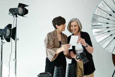 A middle-aged lesbian couple looking at printed photo in a photo studio clipart