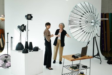 Bir fotoğraf stüdyosunda orta yaşlı bir lezbiyen çift; biri fotoğrafçı ve diğeri de model..