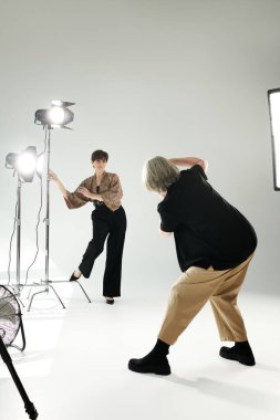 A middle-aged lesbian couple in a bustling photo studio; one expertly capturing moments with a camera, the other striking poses as the model. clipart