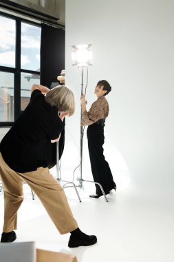 Stüdyoda orta yaşlı lezbiyen bir çift. Fotoğrafçı modelin fotoğrafını çekiyor..