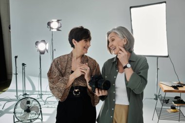 Orta yaşlı bir lezbiyen çift fotoğraf stüdyosunda kamera önünde sohbet ediyor.