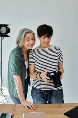 Modern bir fotoğraf stüdyosunda profesyonel kameraya bakan iki orta yaşlı kadın..
