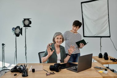Orta yaşlı lezbiyen bir çift profesyonel bir fotoğraf stüdyosunda dizüstü bilgisayarla birlikte çalışıyor..