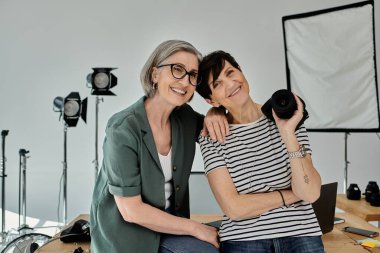 Orta yaşlı lezbiyen çift şık bir fotoğraf stüdyosunda neşe içinde poz veriyor..