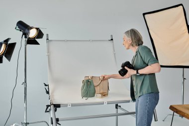 Yeşil gömlekli orta yaşlı bir fotoğrafçı zarafetle bir çanta tutuyor..
