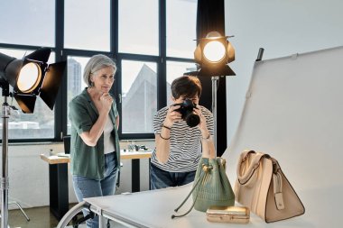 Profesyonel fotoğraf stüdyosunda bir kadın çantaların fotoğrafını çekiyor.
