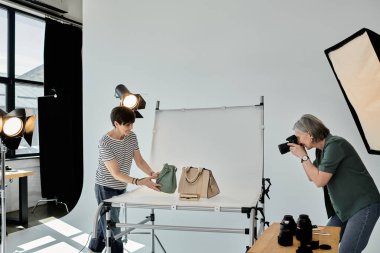Bir fotoğrafçı modern bir stüdyo ortamında fotoğraf makinesinin objektifinden moda çantaları yakalar..