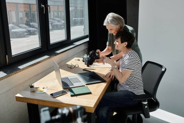 women engaging in a creative task together at a desk in a modern studio setting. clipart