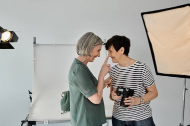 Modern bir fotoğraf stüdyosunda birleşmiş orta yaşlı lezbiyen bir çift güven ve takım çalışması yayıyorlar..