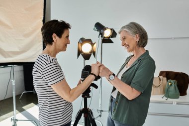 two women, lesbian couple, holding hands while standing together in studio clipart