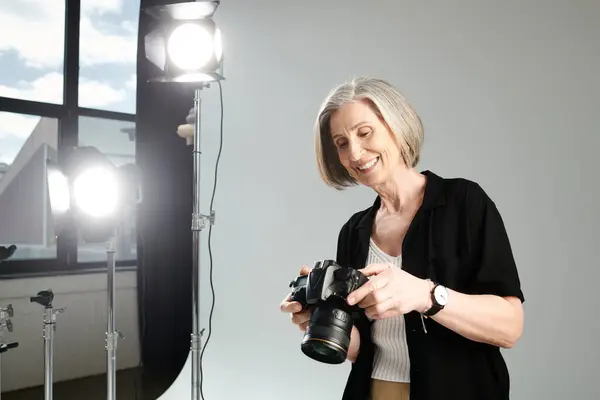 Stock image Middle-aged woman holds a camera, capturing the vibrant light.
