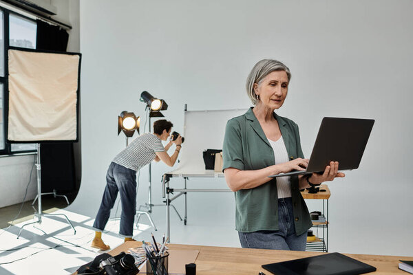 Woman with short hair stands at laptop in sleek office, collaborating on project.