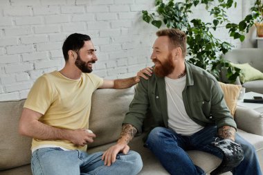 İki sakallı adam rahat bir kanepede oturup maç izleyip birlikte güzel vakit geçiriyorlar..