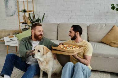 İki sakallı adam pizza yerken sadık Labrador köpekleri sıcak bir oturma odasında onlara katılıyor..