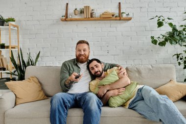 Bir çift sakallı adam oturma odasındaki şık bir kanepenin üstünde gevşeyip eğleniyorlar..