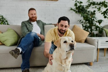 Bir adam ve köpeği, eşcinsel bir çift, oturma odasındaki kanepede rahat bir anı paylaşıyorlar..