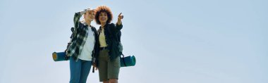 İki genç kadın, biri sarı saçlı, biri siyah kıvırcık saçlı, ıssız bir bölgede birlikte yürüyüş yapıyorlar..
