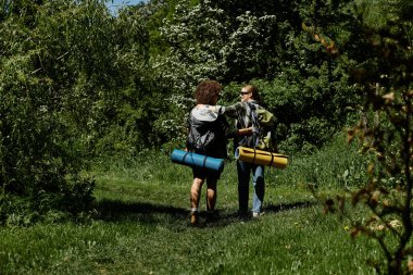 İki genç kadın, lezbiyen bir çift, yemyeşil bir ormanda birlikte yürüyüş yapıyorlar..