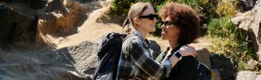 A young lesbian couple hikes through the woods, enjoying the outdoors and each others company. clipart