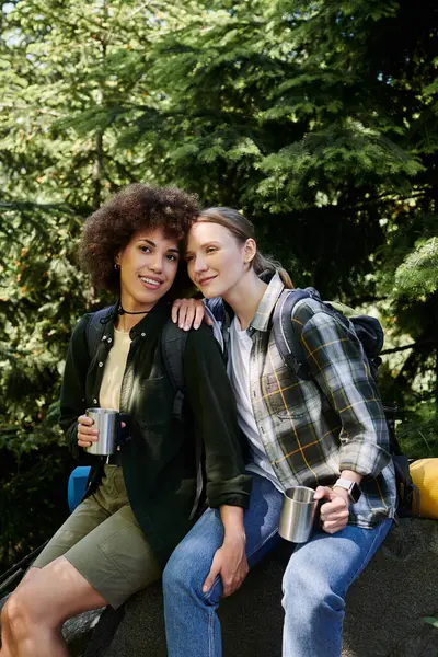 stock image Two young women, one with curly brown hair and one with straight blonde hair, are hiking in the woods together.