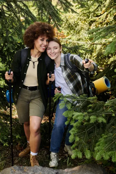 stock image Two young women hike through a lush forest, enjoying their time together outdoors.
